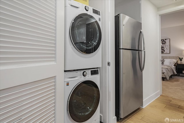 laundry room featuring stacked washer / drying machine and light wood-type flooring