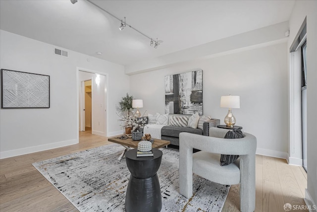 living room with light hardwood / wood-style floors and track lighting