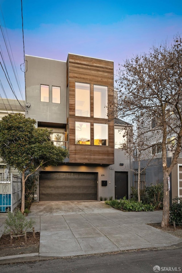 modern home featuring an attached garage, concrete driveway, and stucco siding