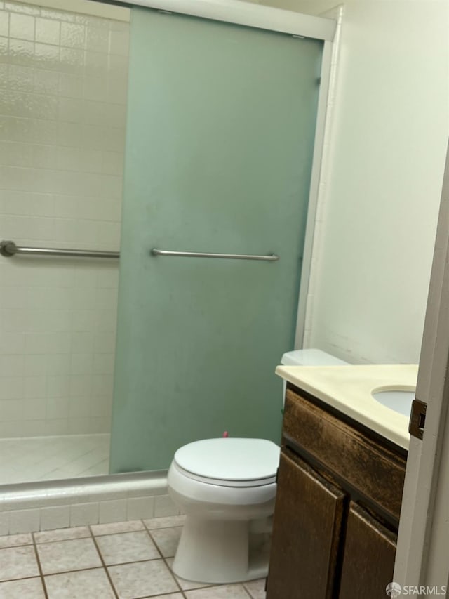 bathroom featuring toilet, an enclosed shower, vanity, and tile patterned flooring