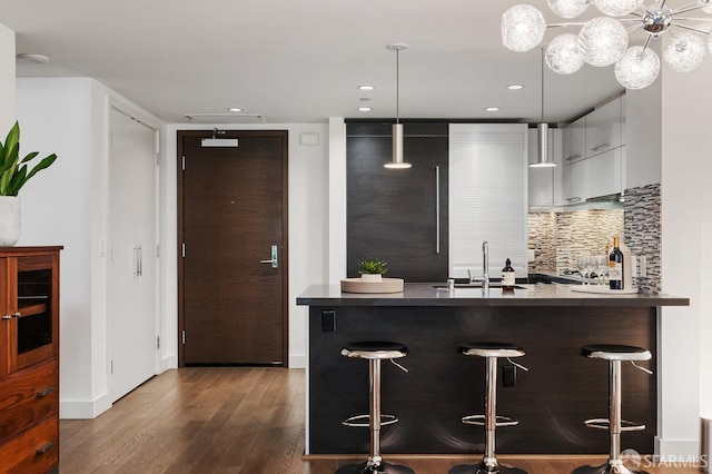 420 Mission Bay Blvd Unit 311, San Francisco, CA 94158 - kitchen featuring modern cabinets, a kitchen bar, dark wood-style flooring, backsplash, and white cabinetry