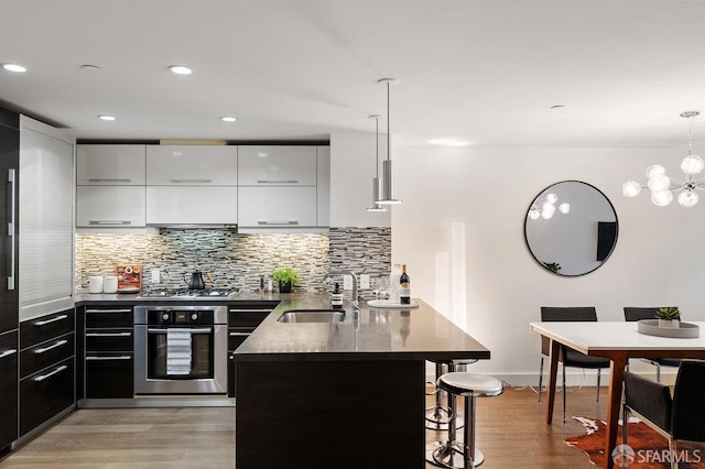 420 Mission Bay Blvd Unit 311, San Francisco, CA 94158 - kitchen featuring stainless steel appliances, a kitchen bar, a peninsula, white cabinetry, and light wood-style flooring