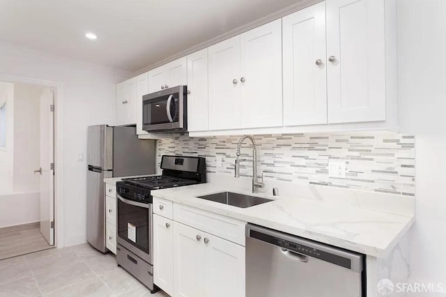 kitchen with stainless steel appliances, white cabinets, a sink, and light stone counters