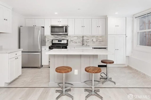 kitchen featuring light countertops, decorative backsplash, appliances with stainless steel finishes, white cabinets, and a sink