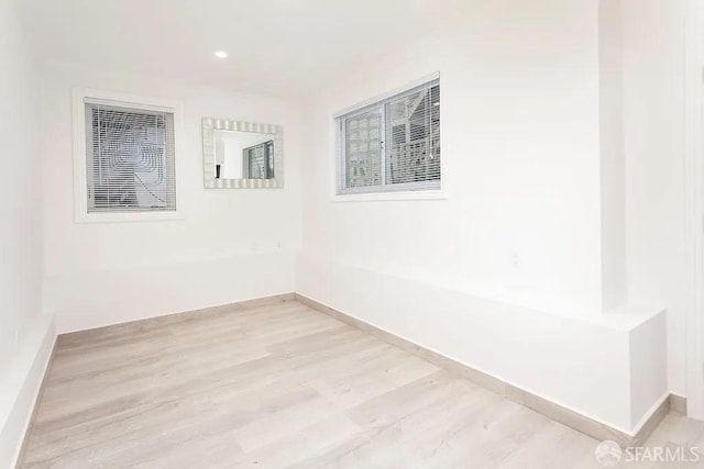 empty room with light wood-style floors, recessed lighting, and baseboards