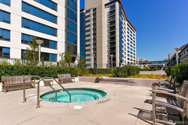 view of swimming pool featuring fence and a hot tub