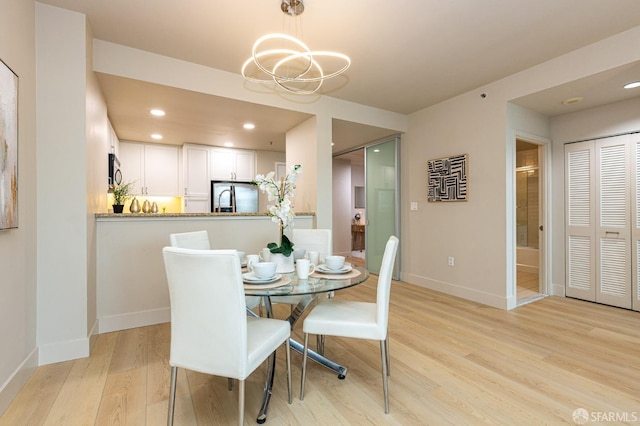 dining room featuring light wood finished floors, baseboards, a chandelier, and recessed lighting