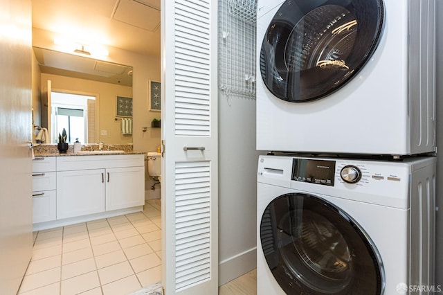 washroom with a sink, laundry area, light tile patterned floors, and stacked washer / dryer