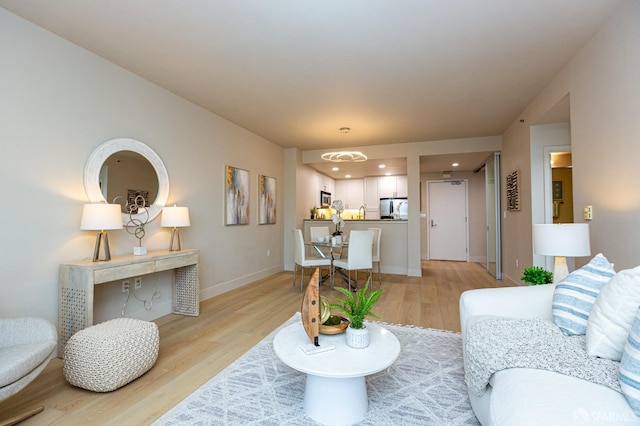 living area featuring recessed lighting, baseboards, and light wood finished floors