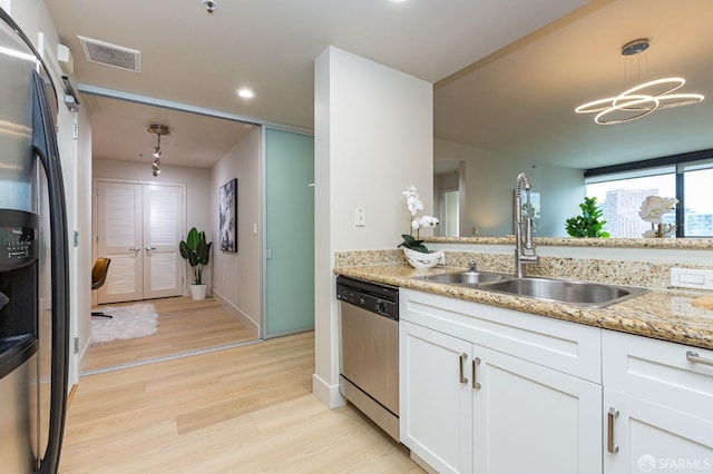 kitchen with visible vents, light wood-style flooring, appliances with stainless steel finishes, white cabinetry, and a sink