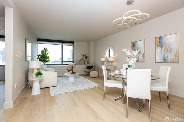 dining area with light wood-style floors, baseboards, and a notable chandelier