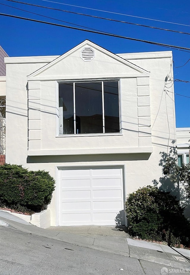 view of side of home with an attached garage and stucco siding