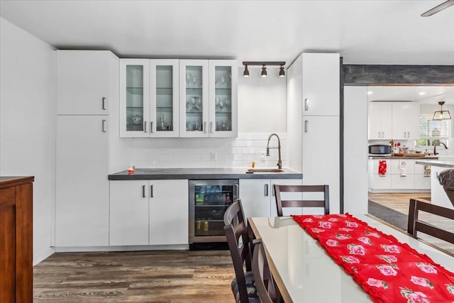 bar featuring tasteful backsplash, white cabinetry, sink, dark wood-type flooring, and beverage cooler