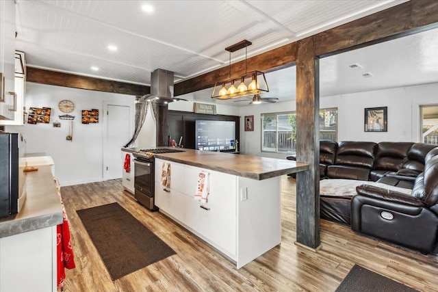 kitchen with light hardwood / wood-style floors, white cabinetry, island exhaust hood, pendant lighting, and stainless steel gas range oven