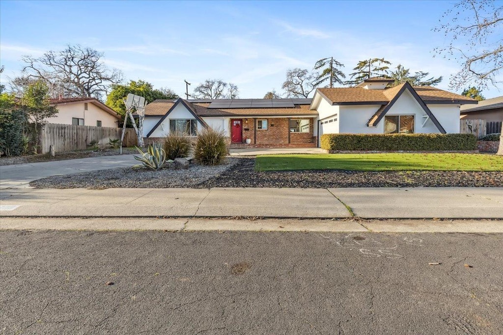 view of front of property with a garage, a front lawn, and solar panels