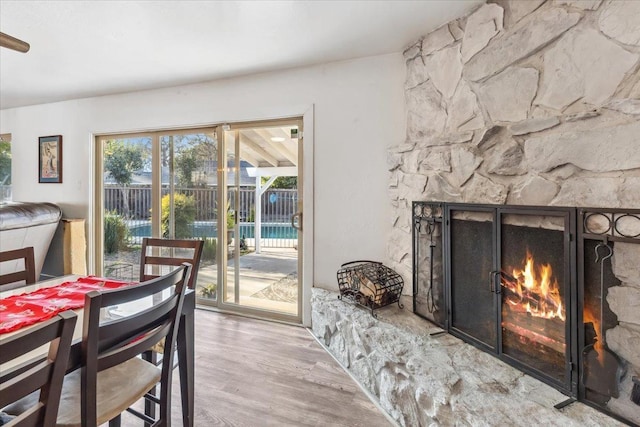 dining space with light hardwood / wood-style floors and a stone fireplace