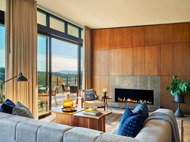 living room with a mountain view, hardwood / wood-style flooring, a wall of windows, and a tile fireplace