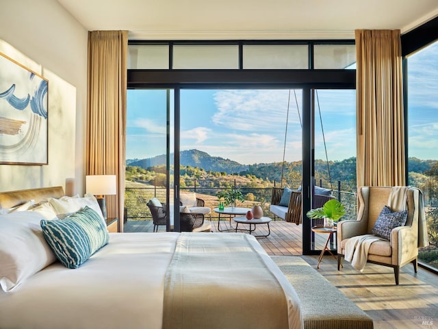 bedroom featuring hardwood / wood-style flooring, a mountain view, multiple windows, and access to outside