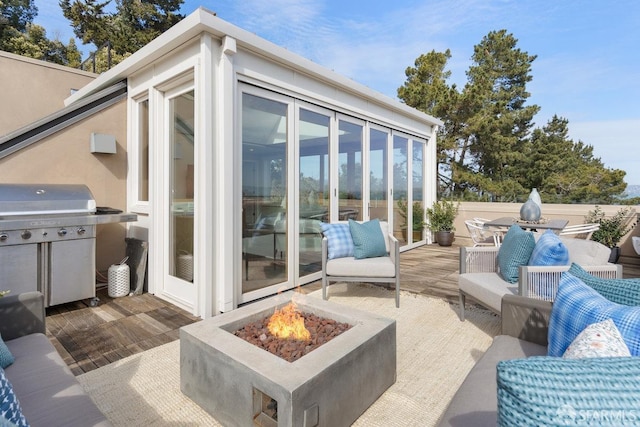 view of patio / terrace featuring grilling area, an outdoor living space with a fire pit, and a sunroom