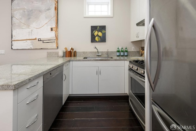 kitchen with a sink, stainless steel appliances, dark wood-type flooring, white cabinets, and extractor fan