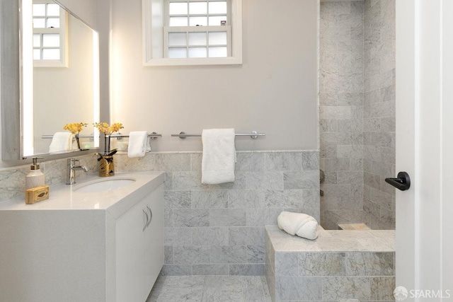 full bathroom with vanity, tile walls, and a wainscoted wall