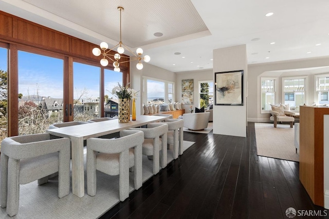 dining area with a notable chandelier, recessed lighting, a raised ceiling, and dark wood-style flooring