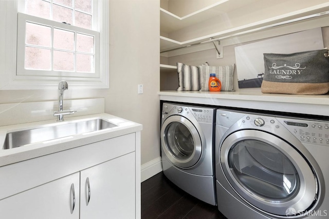 laundry room with baseboards, washing machine and dryer, dark wood-style flooring, and a sink