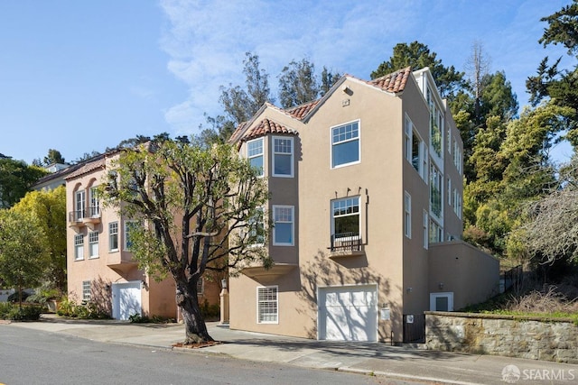 view of front of house with stucco siding, a tile roof, and a garage