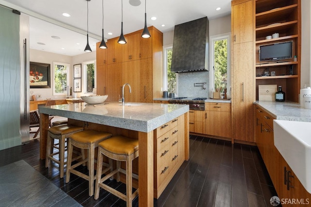 kitchen with dark wood finished floors, wall chimney range hood, a healthy amount of sunlight, and stainless steel gas stovetop