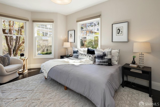 bedroom featuring multiple windows, baseboards, and wood finished floors