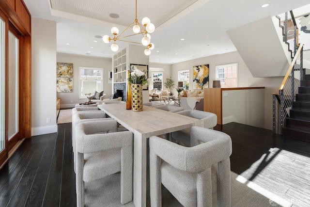 dining space with stairs, a raised ceiling, recessed lighting, and dark wood finished floors