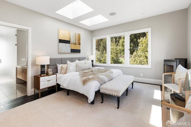 bedroom with baseboards, wood finished floors, and a skylight