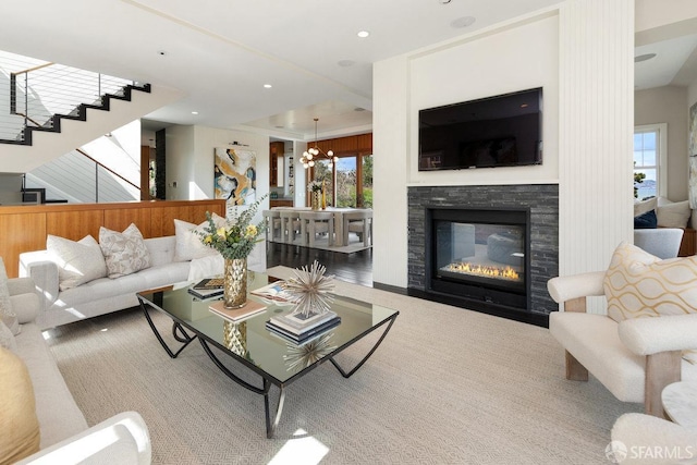 living room with a stone fireplace, recessed lighting, stairway, and an inviting chandelier