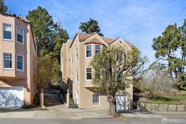 view of front of home with stucco siding, a tiled roof, and a garage