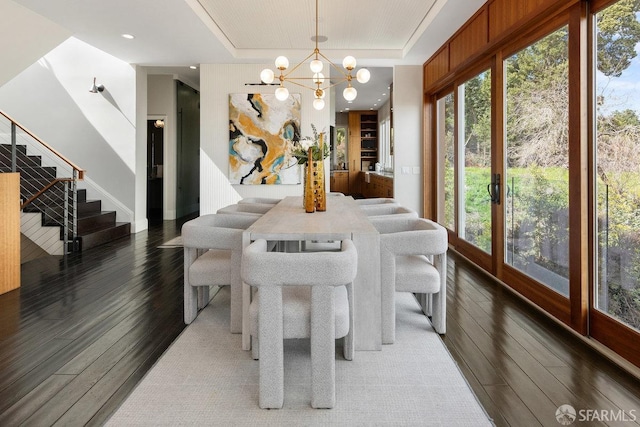 dining area featuring hardwood / wood-style floors, a tray ceiling, stairs, and plenty of natural light