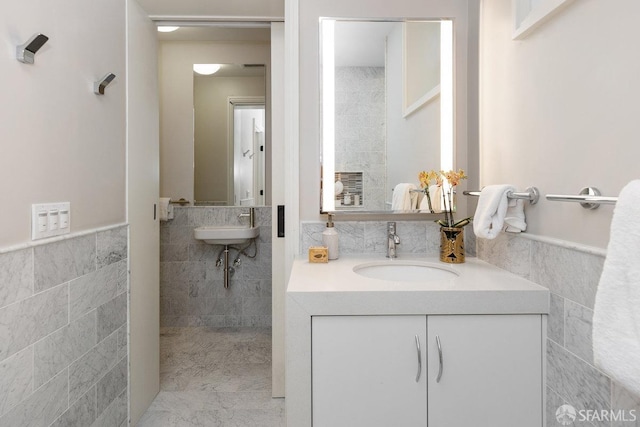 bathroom with a sink, a wainscoted wall, and tile walls