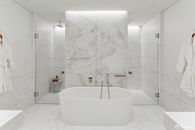 full bathroom featuring marble finish floor, a marble finish shower, tile walls, and a freestanding bath