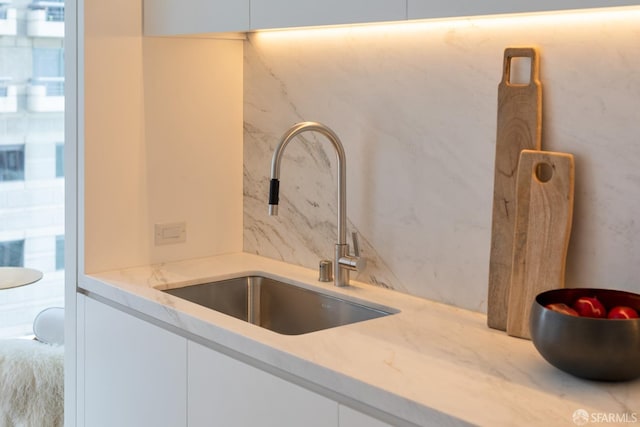 interior details with white cabinetry and a sink