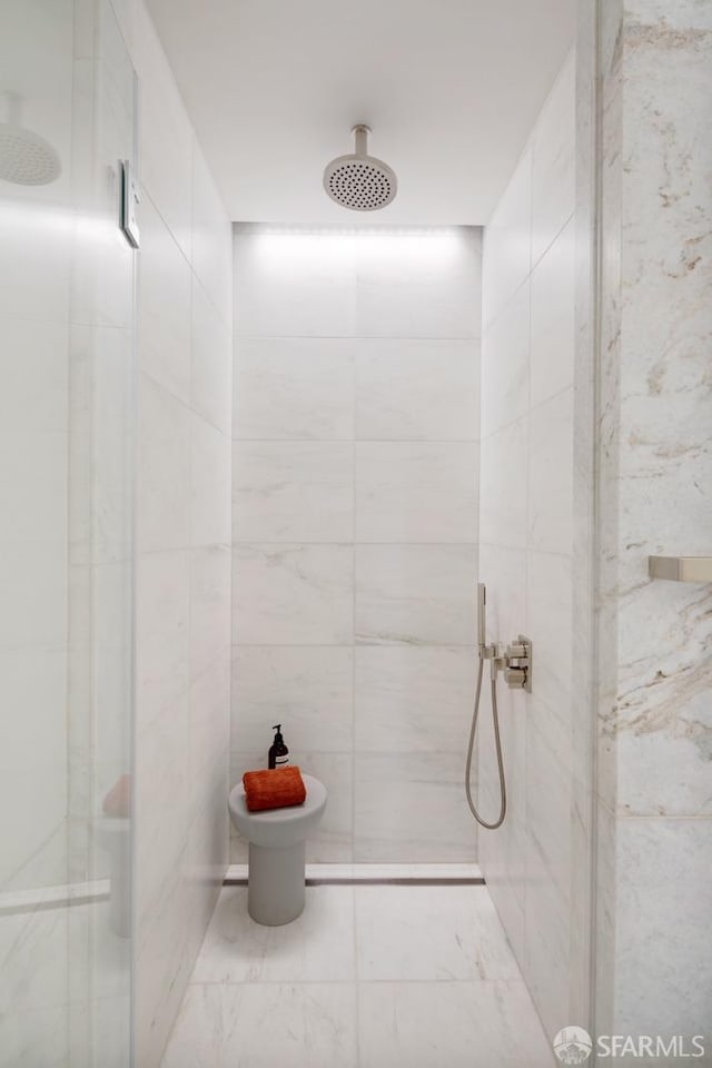 full bath featuring tiled shower and tile walls