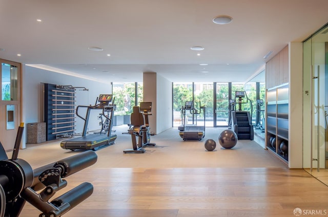 workout area with a wall of windows, recessed lighting, and wood finished floors