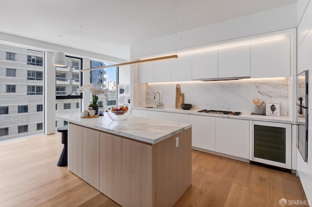 kitchen featuring wine cooler, a sink, gas stovetop, backsplash, and modern cabinets