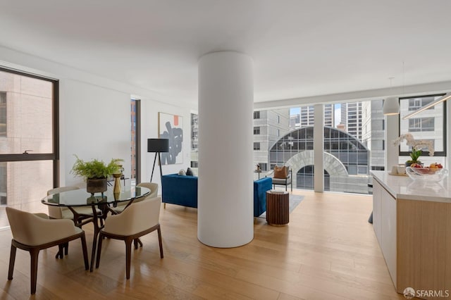 dining room featuring expansive windows, decorative columns, and light wood finished floors