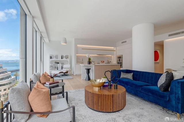 living room featuring light wood-style floors, visible vents, and a wall of windows