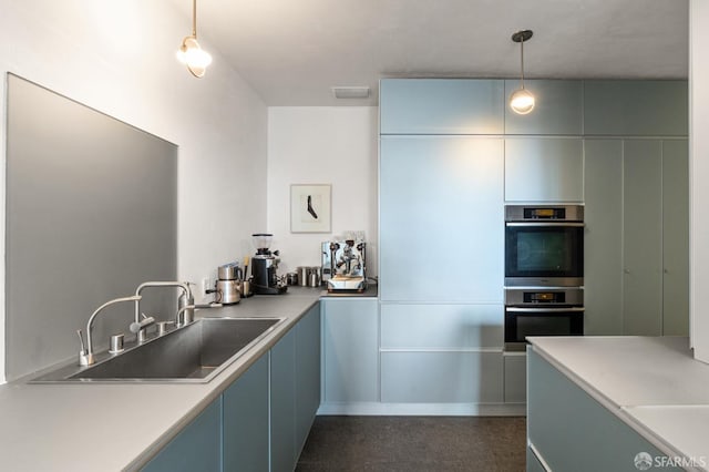 kitchen featuring visible vents, hanging light fixtures, light countertops, stainless steel double oven, and a sink