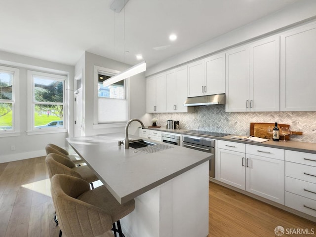 kitchen with sink, oven, a kitchen breakfast bar, hanging light fixtures, and decorative backsplash