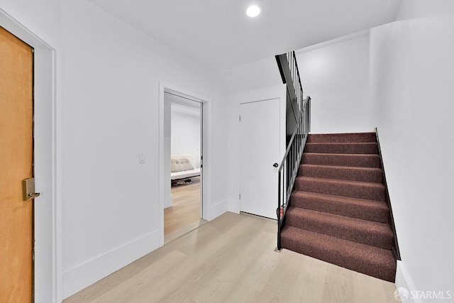 staircase featuring baseboards, wood finished floors, and recessed lighting