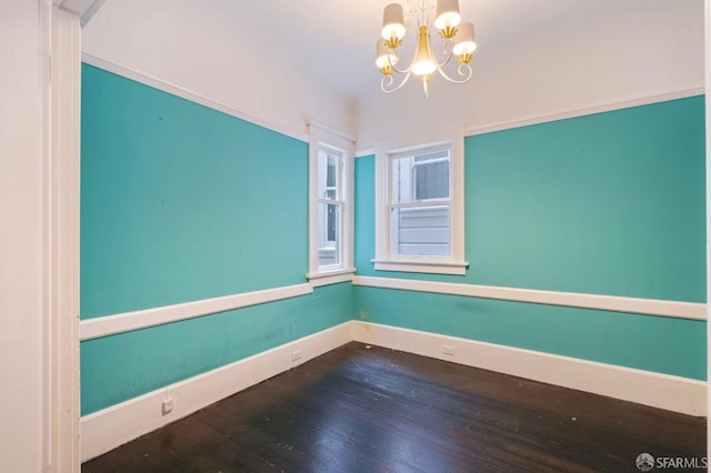 empty room featuring wood-type flooring and a chandelier