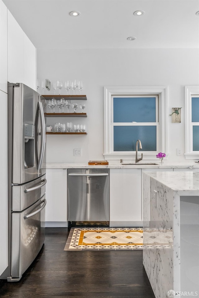 kitchen featuring light stone counters, dark hardwood / wood-style floors, sink, white cabinetry, and stainless steel appliances