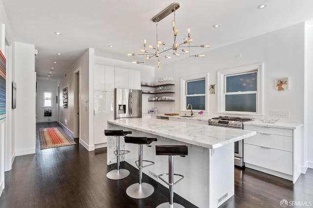 kitchen featuring appliances with stainless steel finishes, white cabinetry, a center island, decorative light fixtures, and dark hardwood / wood-style floors