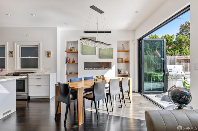 dining space with built in shelves and dark hardwood / wood-style flooring